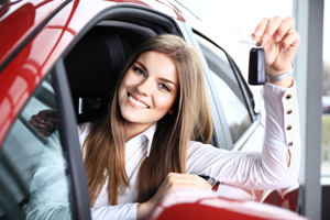 Young woman holding keys in her new car